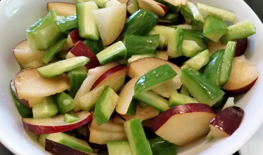 Choped plum and cucumbers tossed together in a bowl