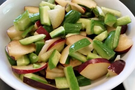 Choped plum and cucumbers tossed together in a bowl