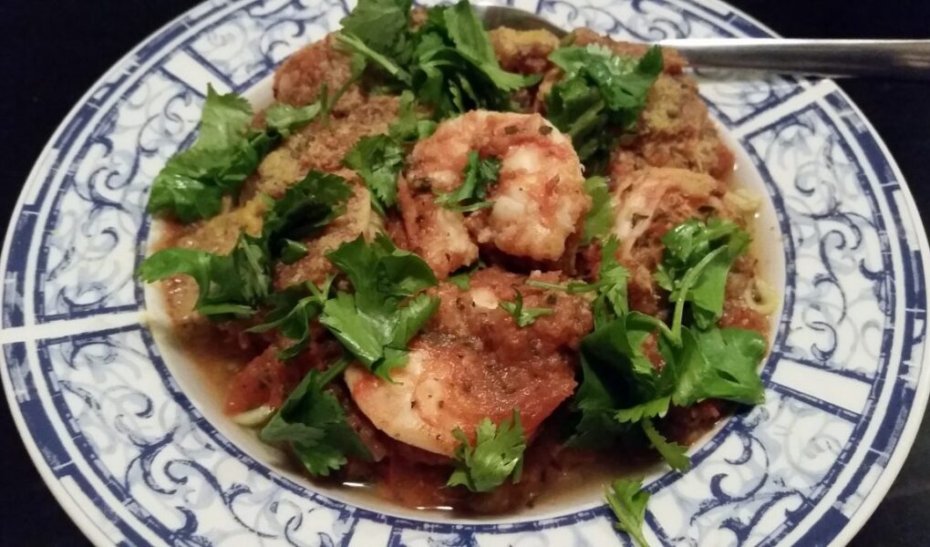 Pasta serving bowl of shrimp divolo garnished with flat leaf parsely