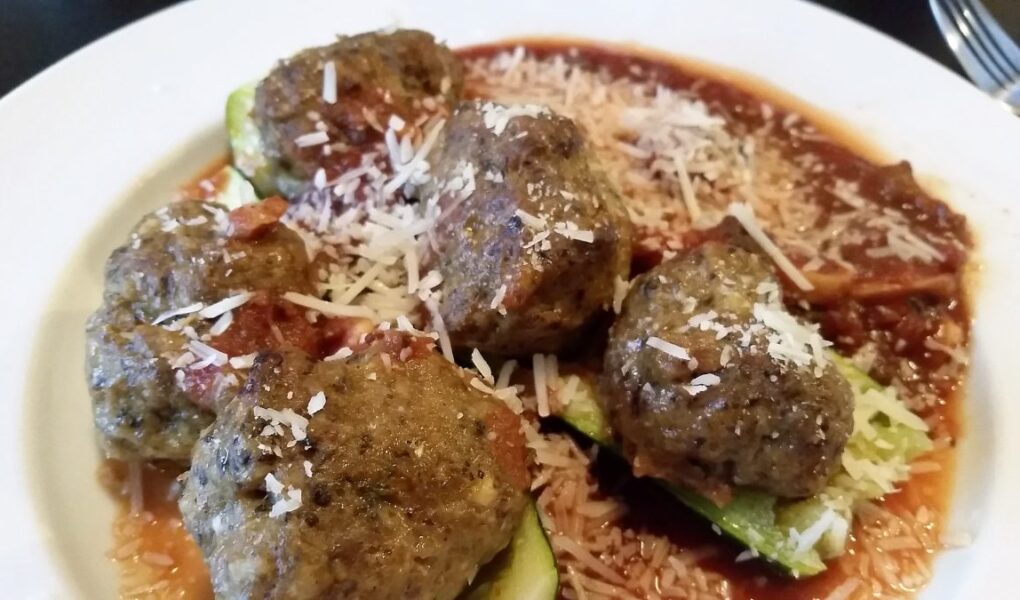 Spicy meatbals served with zuchinni and sauce in white soup bowl