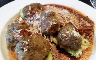 Spicy meatbals served with zuchinni and sauce in white soup bowl