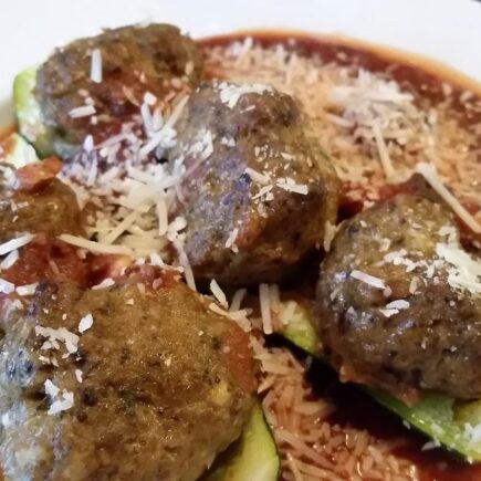 Spicy meatbals served with zuchinni and sauce in white soup bowl