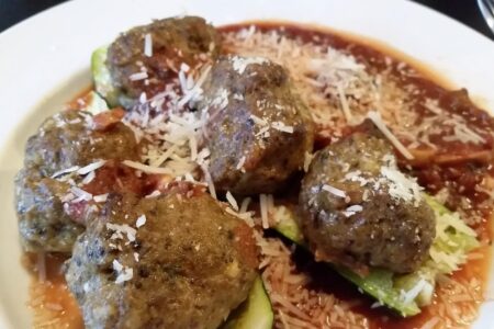 Spicy meatbals served with zuchinni and sauce in white soup bowl