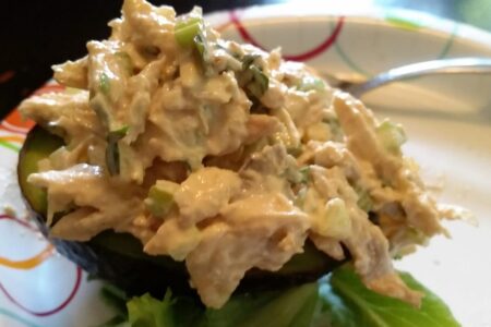 Finished chicken salad served on half an avocado on paper plate