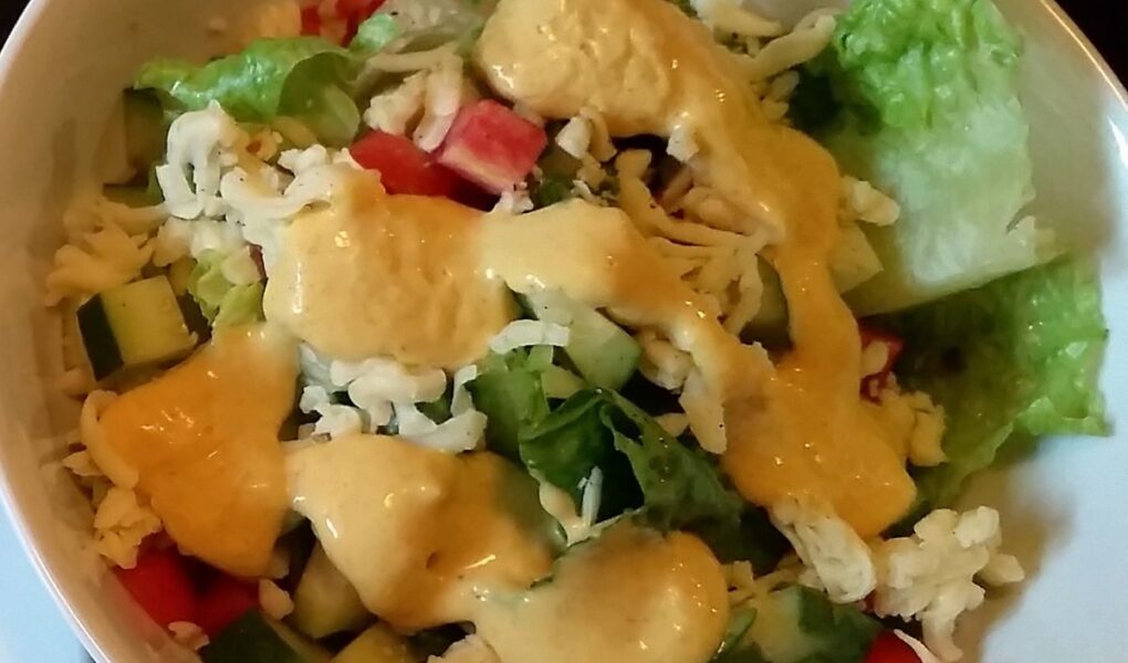 Finish vinaigrette poured over tossed salad in white bowl