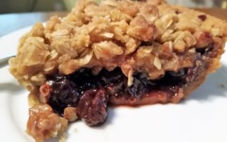 Side view of jam crumble pie on a white dessert plate