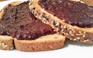 LS Grape-Cherry Jam spread on two slices of sesame toast on a white salad plate