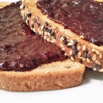 LS Grape-Cherry Jam spread on two slices of sesame toast on a white salad plate