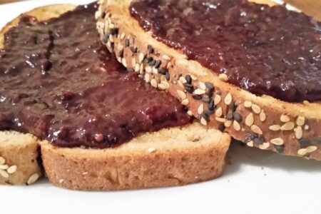 LS Grape-Cherry Jam spread on two slices of sesame toast on a white salad plate
