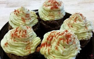 Close-up of black serving plate with five finished liver cupcakes topped with decorative mashed yams and sprinkled with paprika