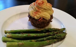 Another view of Individual liver cupcake with mashed yam topping served alongside roasted aspragus on a white diner plate