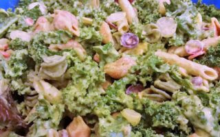 Close up of salad showing kale, dressing along with penne and spiral pasta and grapes