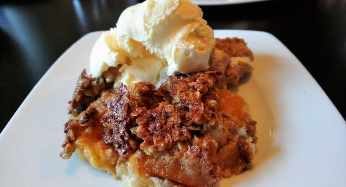 Peaches and Cream Cobbler on plate, topped with scoop of vanilla ice cream