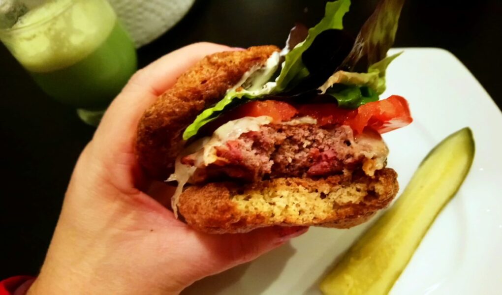 YiaYia holding Burger served on Psyllium Husk Bread viewed from side