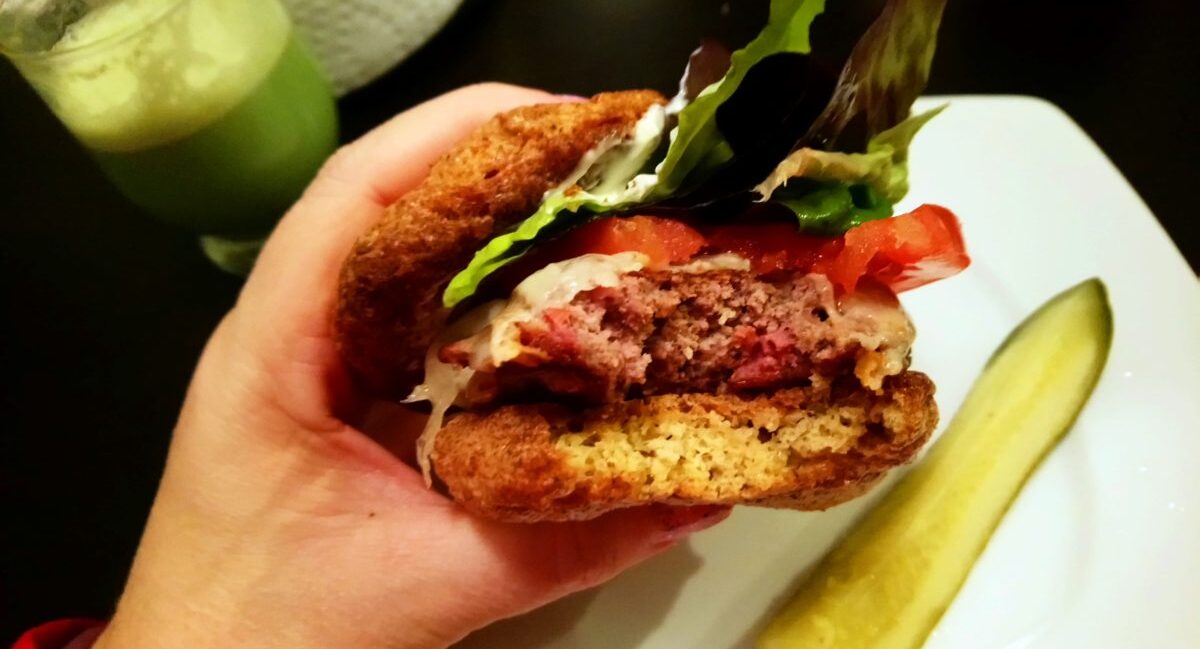 YiaYia holding Burger served on Psyllium Husk Bread viewed from side