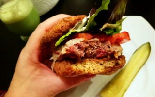 YiaYia holding Burger served on Psyllium Husk Bread viewed from side