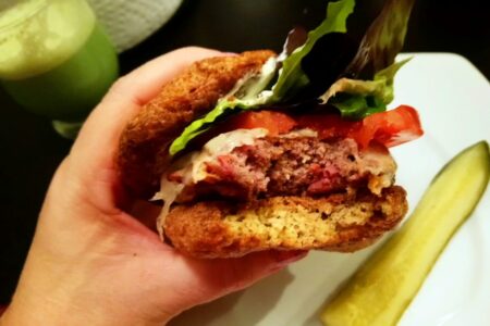 YiaYia holding Burger served on Psyllium Husk Bread viewed from side